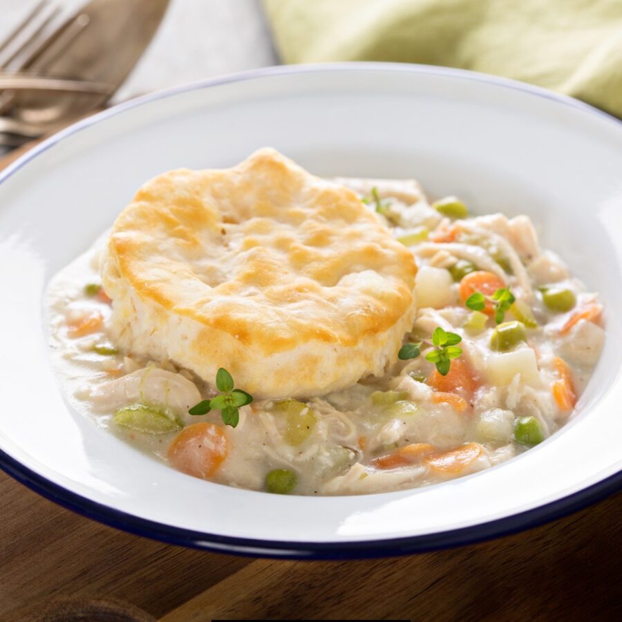 Slow Cooker Chicken Pot Pie  in a white bowl with a biscuit on top