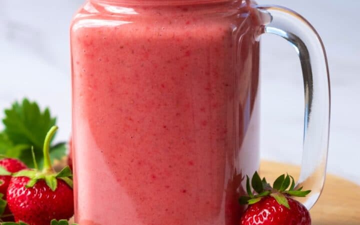 Strawberry Smoothie in a glass mug with strawberries to garnish