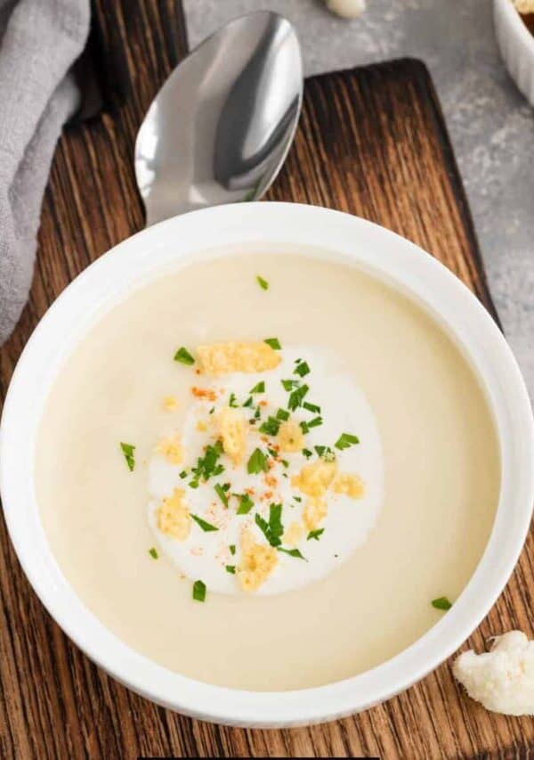 Overhead image of cauliflower cheese soup in a white bowl