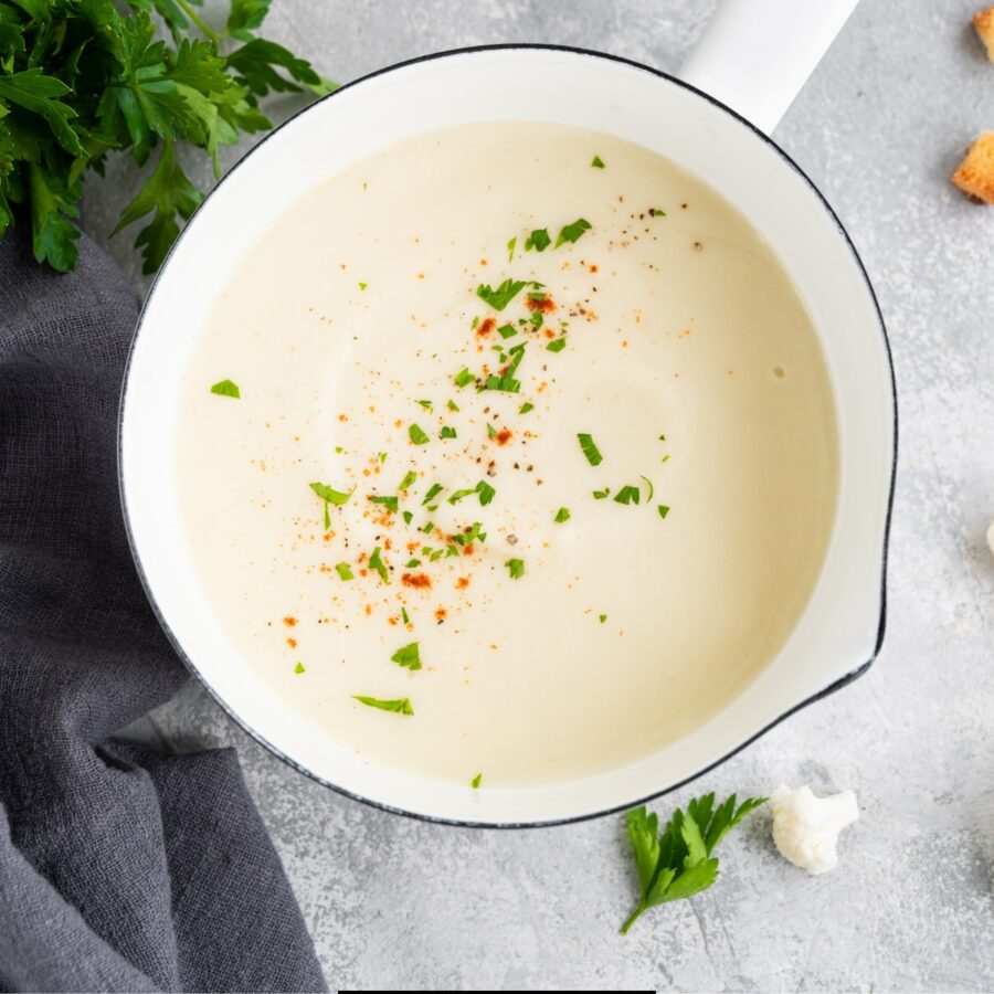 close up image of cauliflower cheese soup in a sauce pan