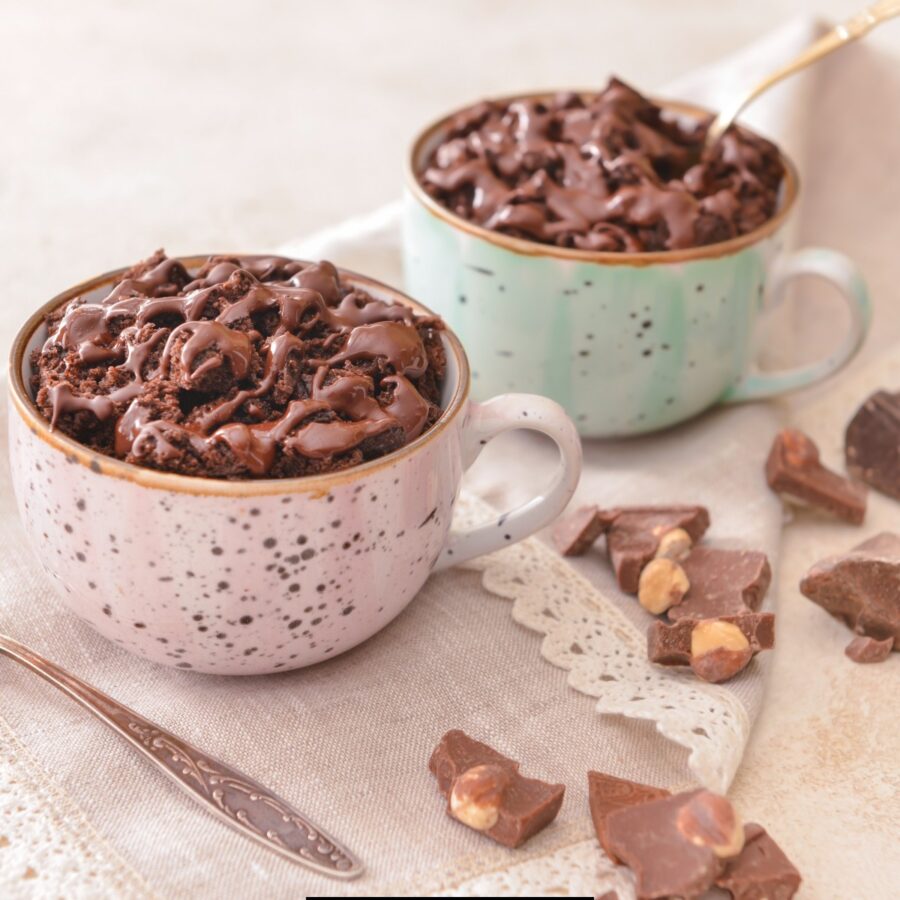 Two servings of coffee mug cake in two different colored mugs