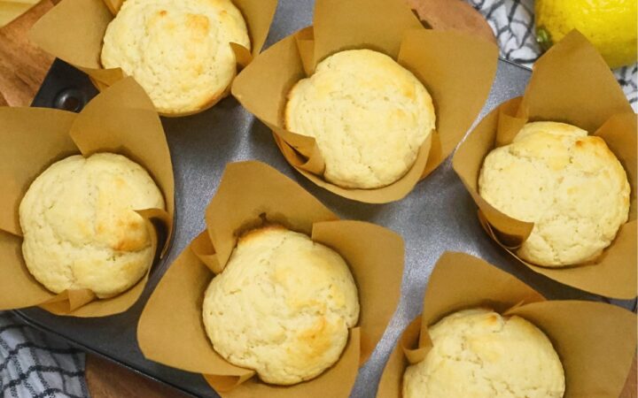 Six baked lemon muffins in a muffin tin