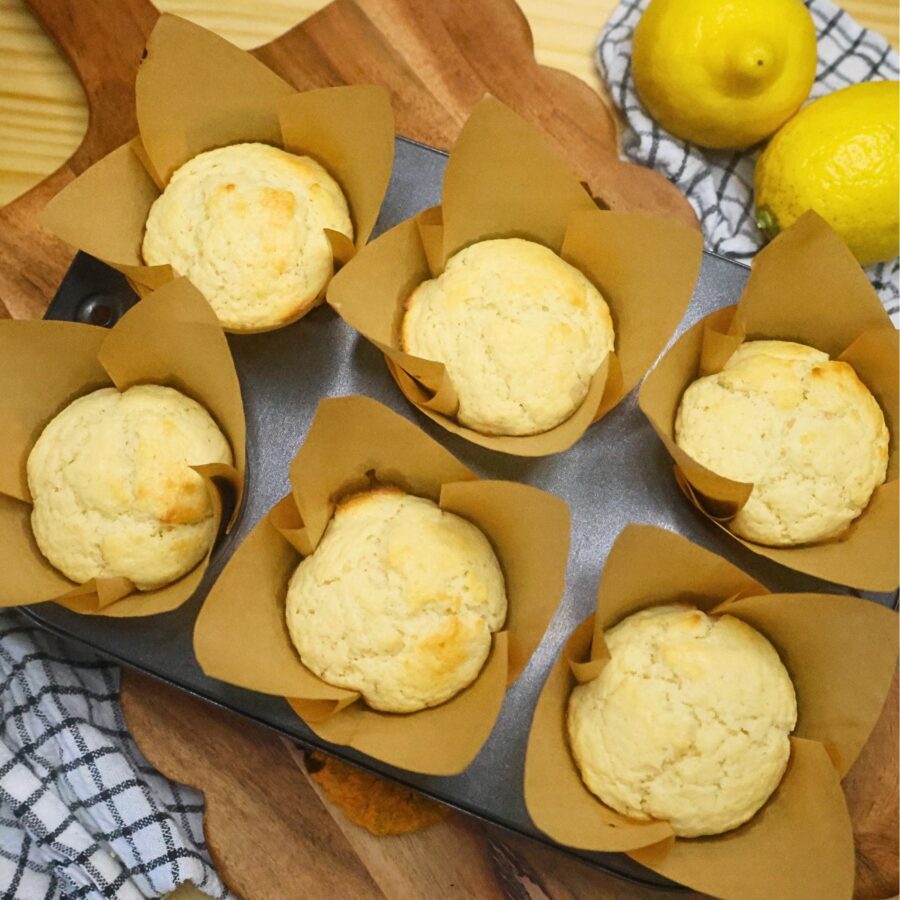 Six baked lemon muffins in a muffin tin