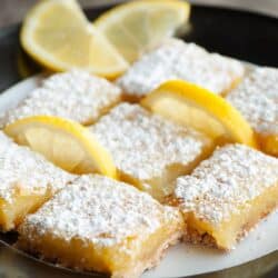 Overhead image of Lemon Squres on a white plate with lemon wedges