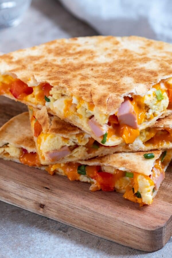 A breakfast quesadilla cut into pieces and stacked on a wooden cutting board