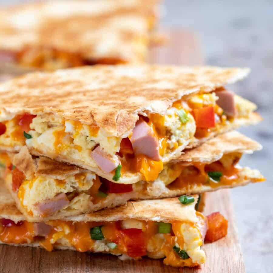 Close up image of a breakfast quesadilla on a wooden cutting board