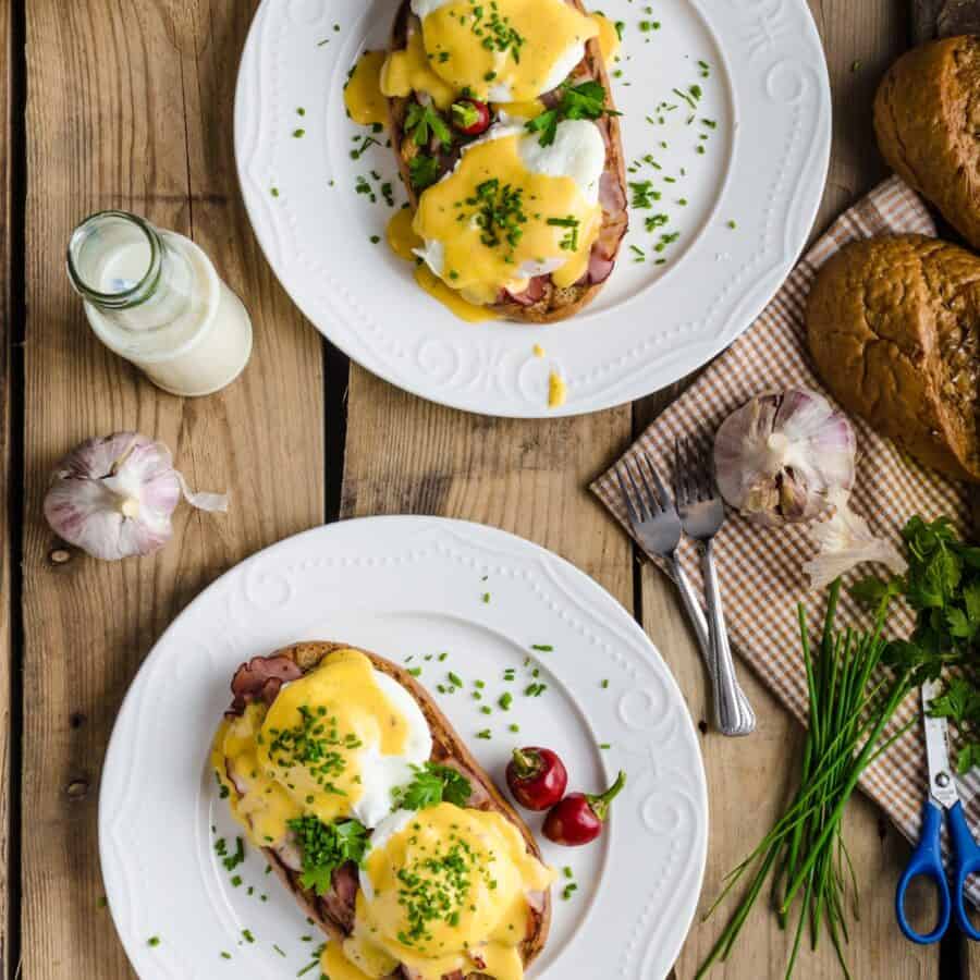 Overhead image of two plates of Eggs Benedict on a wooden table