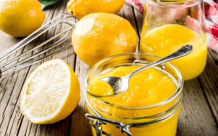 Lemon curd in jars with lemons surrounding it