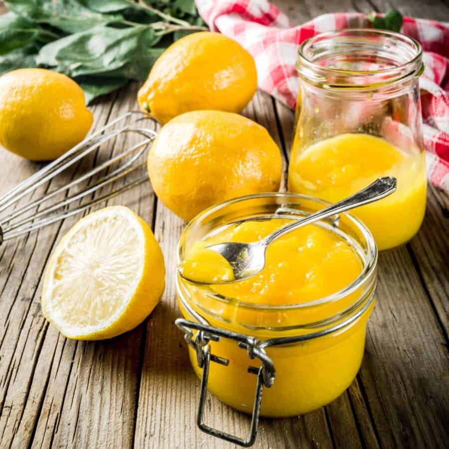 Lemon curd in jars with lemons surrounding it