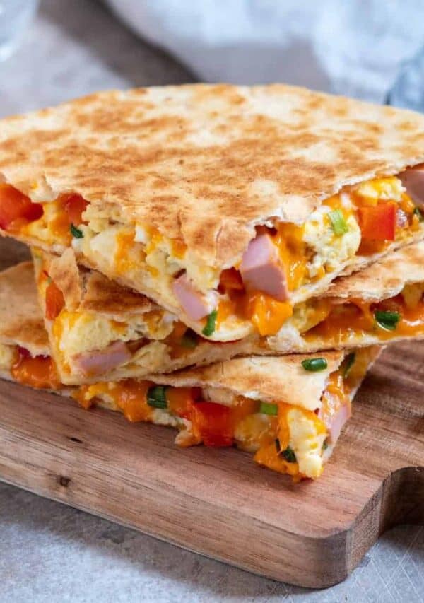 A breakfast quesadilla cut into pieces and stacked on a wooden cutting board