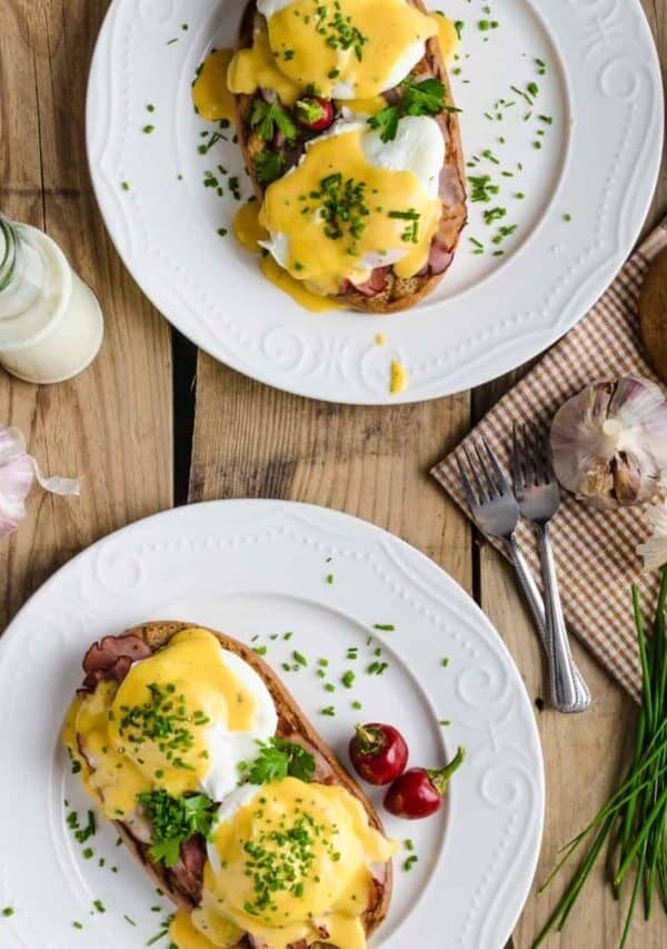 Overhead image of two plates of Eggs Benedict on a wooden table