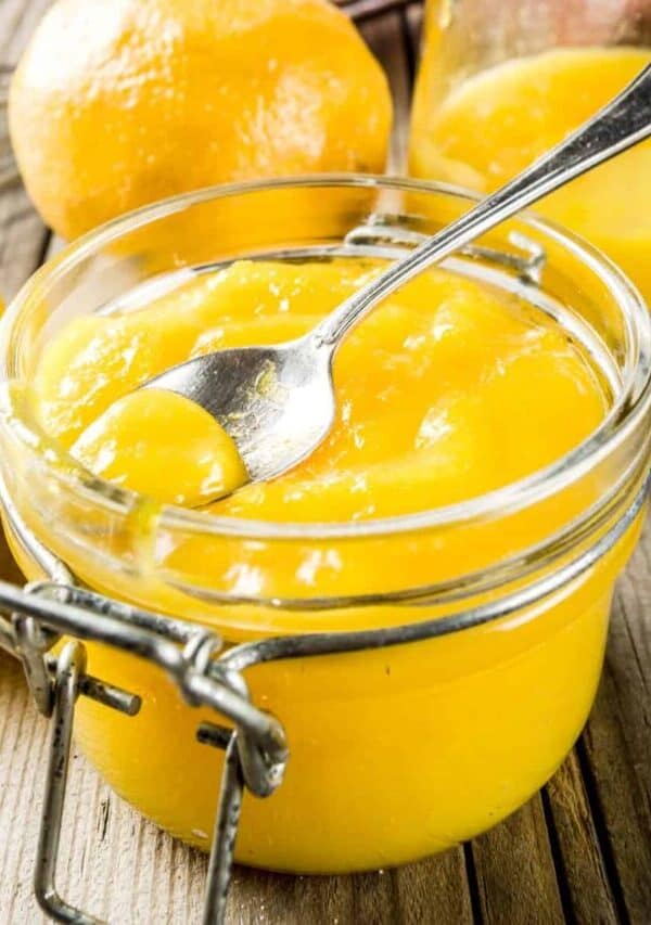 Lemon Curd in a glass jar with a spoon in it