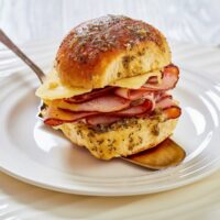 Close up image of a Hawaiian roll slider being served on a white place