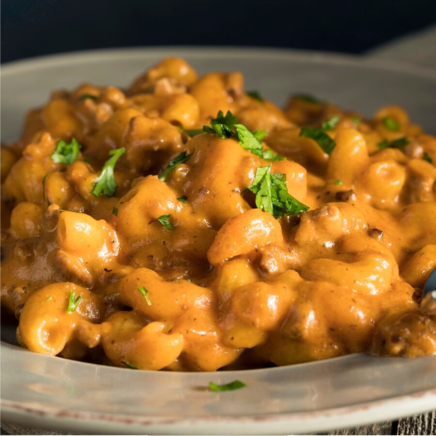 A serving of Cheeseburger Mac on a white plate with a parsley garnish