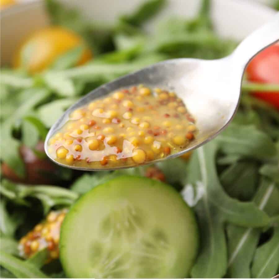 Dijon Vinaigrette being drizzled over a salad with a spoon