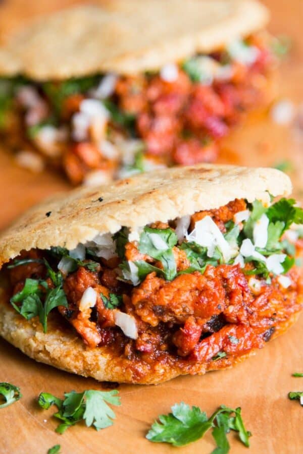 Two filled gorditas on a wooden cutting board