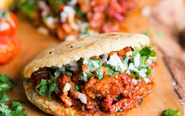 Two filled gorditas on a wooden cutting board