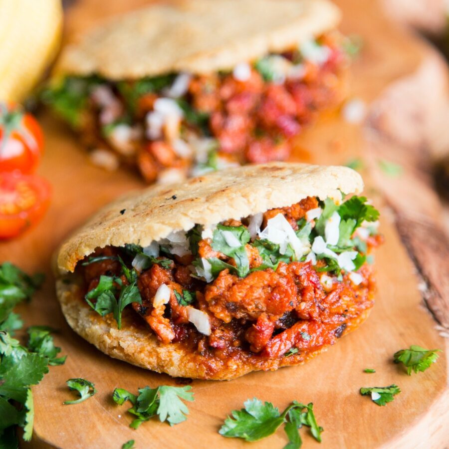 Two filled gorditas on a wooden cutting board