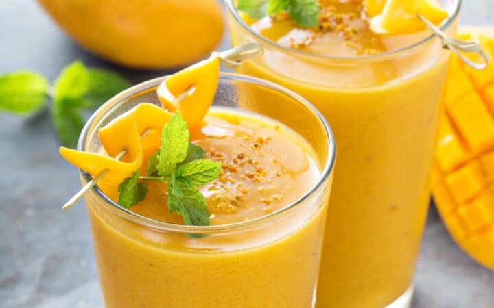 Two Mango Smoothies in glasses with mango and mint garnish