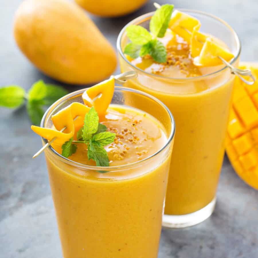 Two Mango Smoothies in glasses with mango and mint garnish