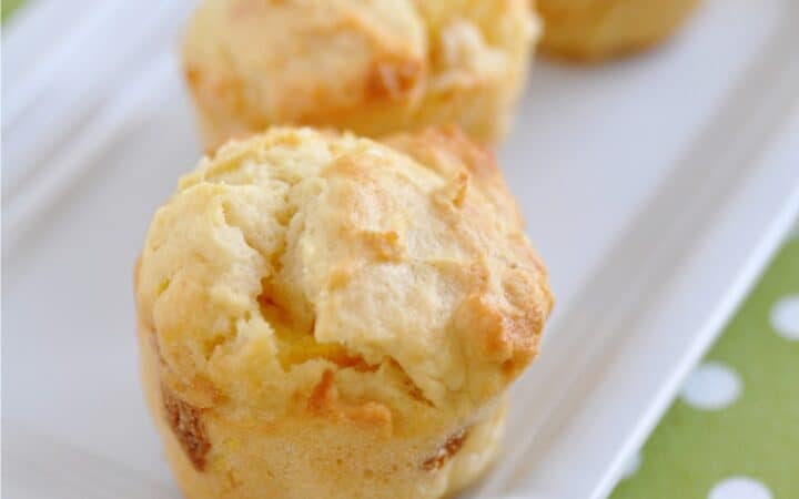 Three Peach Muffins on a white platter with a green and white tablecloth