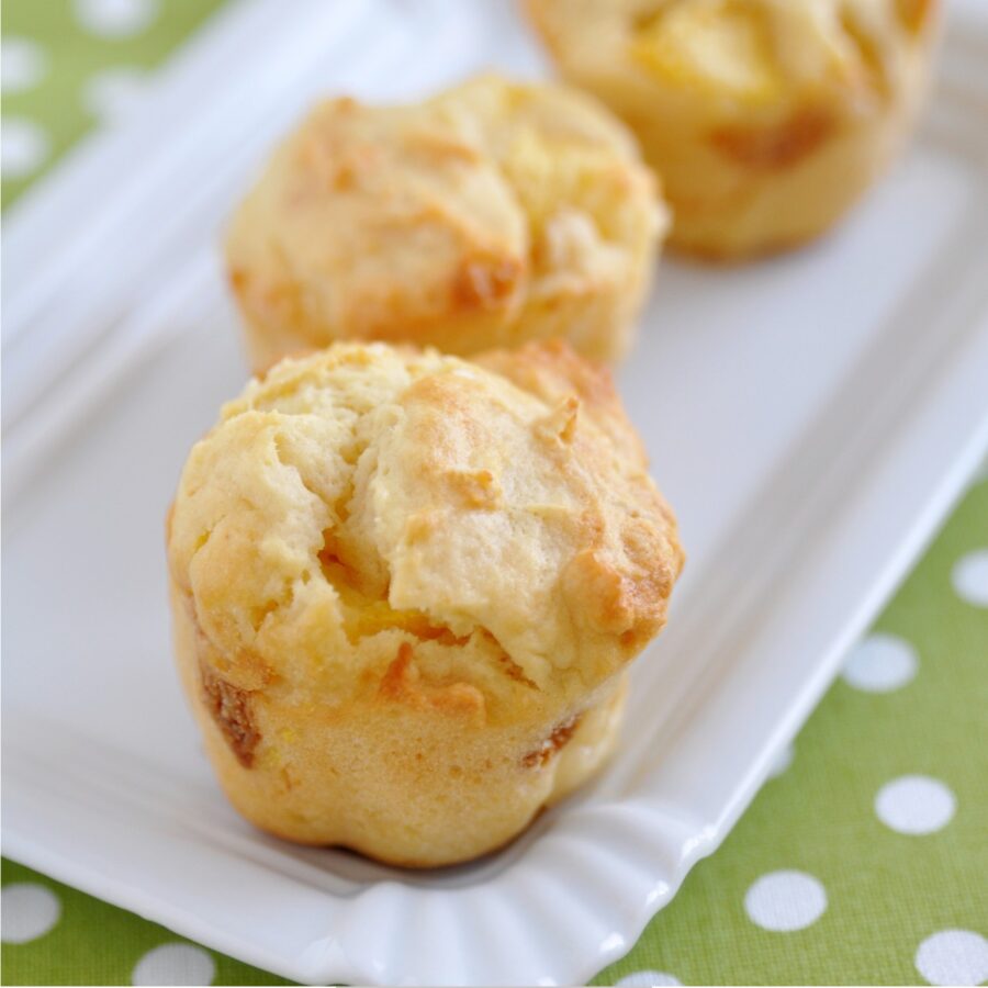 Three Peach Muffins on a white platter with a green and white tablecloth
