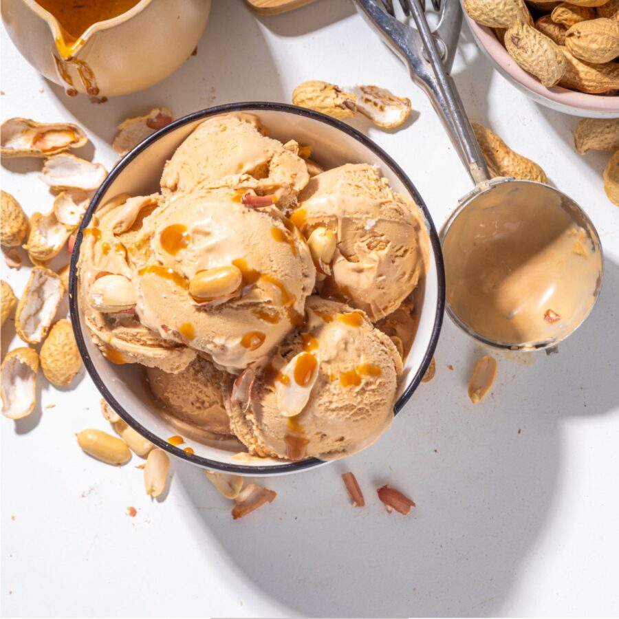 Overhead image of Peanut Butter Ice Cream in a bowl with peanuts scattered around it