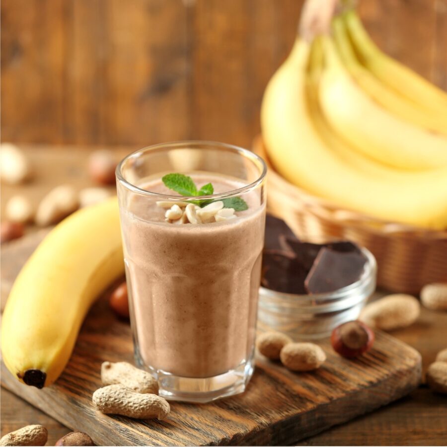 Protein Smoothie on a rusting table with peanuts and bananas