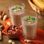Two Protein Smoothies in glasses next to peanuts and bananas - 8