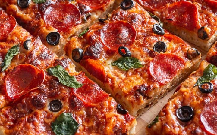 Close up image of a sheet pan pizza cut into pieces