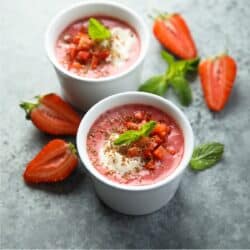 Two Bowls of Strawberry Soup with sliced strawberries and mint next to them