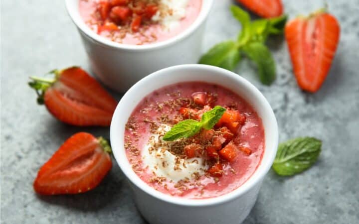 Two Bowls of Strawberry Soup with sliced strawberries and mint next to them