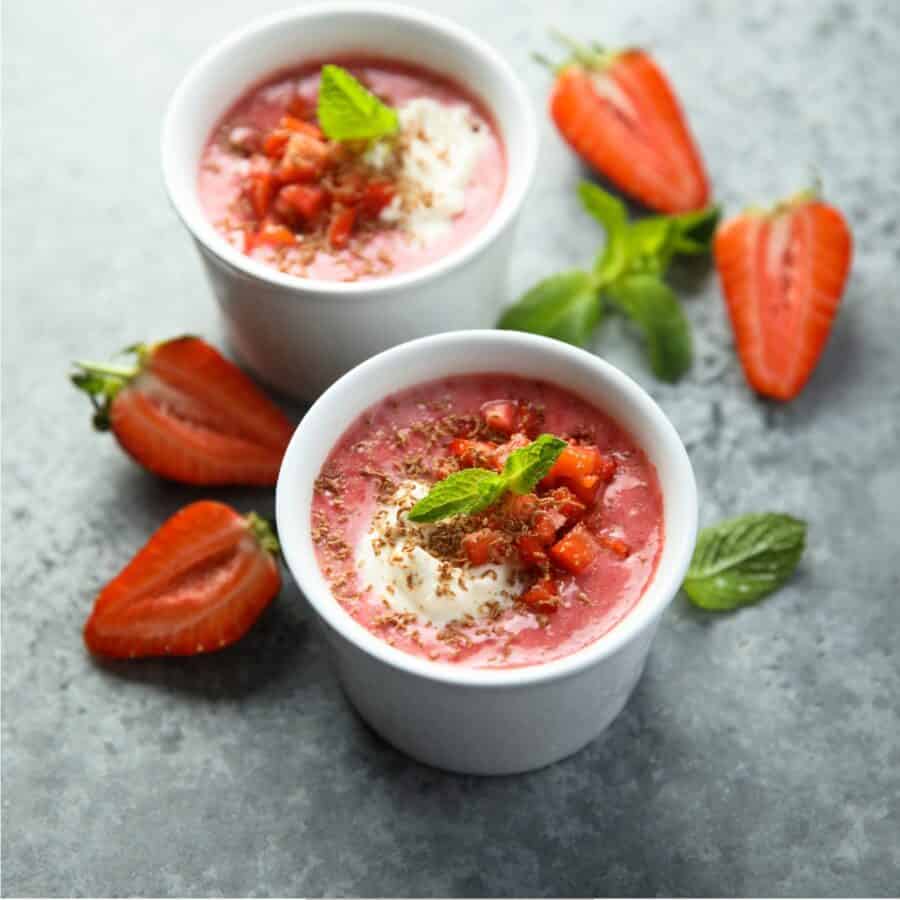 Two Bowls of Strawberry Soup with sliced strawberries and mint next to them
