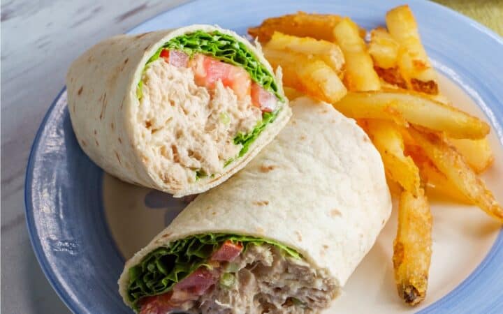 Overhead image of a Tuna Wrap cut in half on a blue and white plate