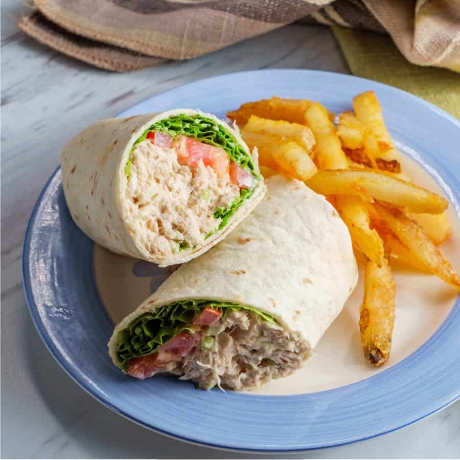 Overhead image of a Tuna Wrap cut in half on a blue and white plate