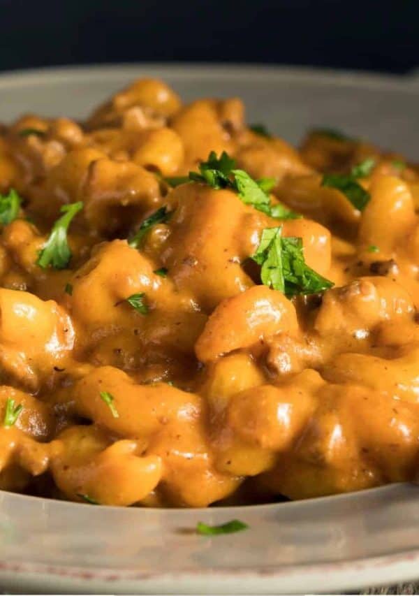 A serving of Cheeseburger Mac on a white plate with a parsley garnish