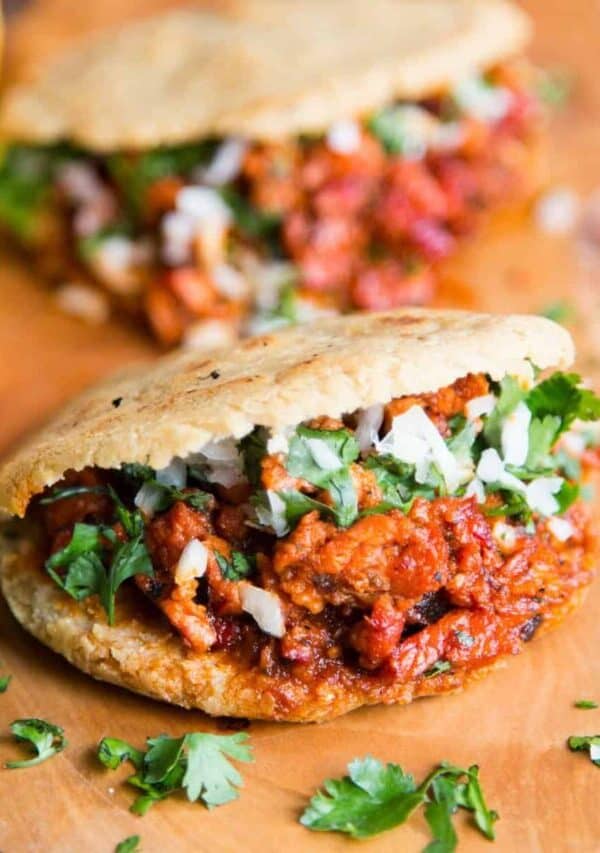Two filled gorditas on a wooden cutting board