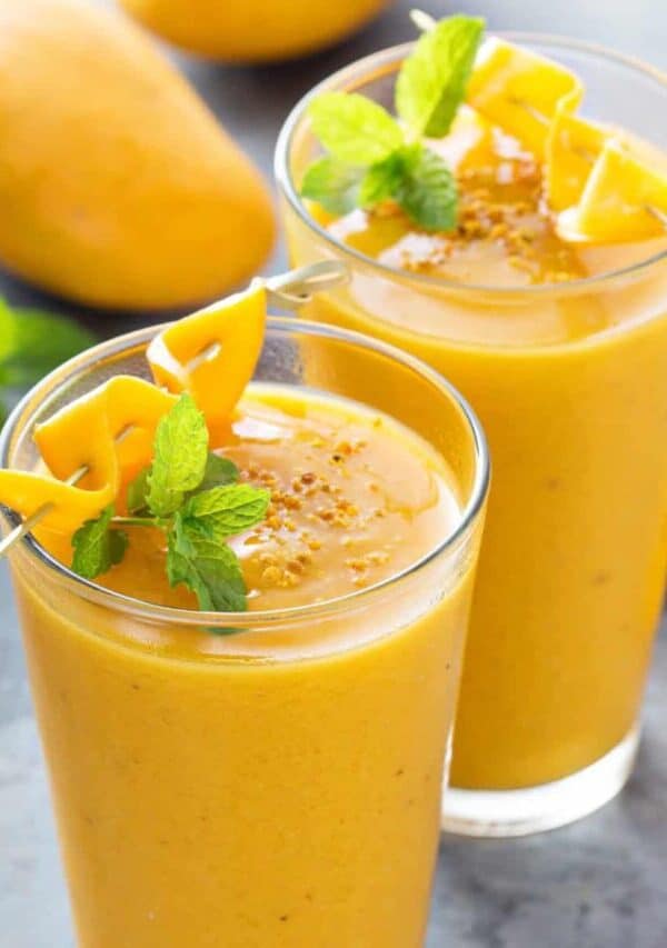 Two Mango Smoothies in glasses with mango and mint garnish