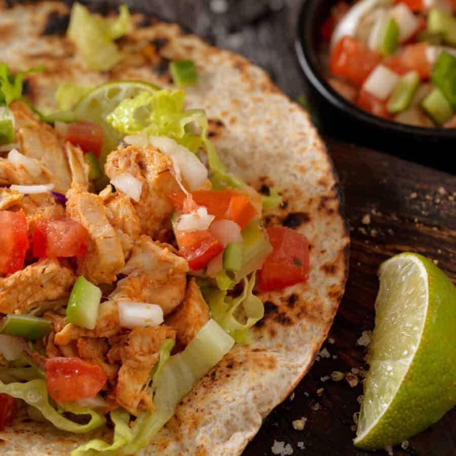 Overhead image of Buffalo Chicken Tacos with sides of pico de gallo and lime