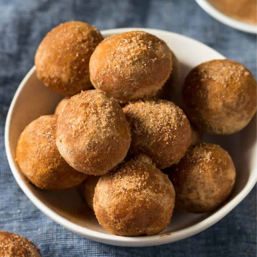 Air Fryer Donut Holes rolled in Cinnamon Sugar in a white bowl