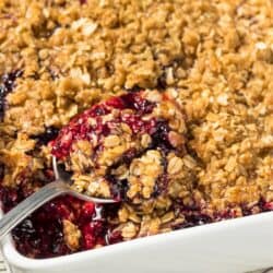 Blackberry Crisp in a white pan with a spoon in it