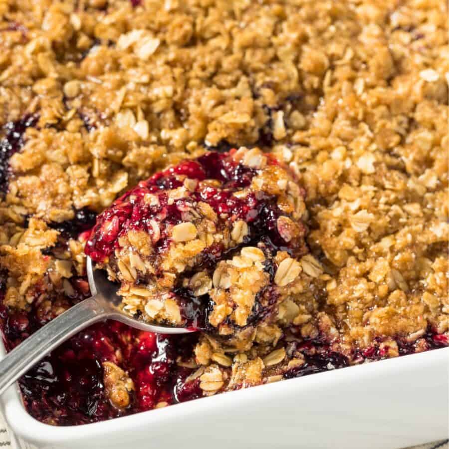 Blackberry Crisp in a white pan with a spoon in it
