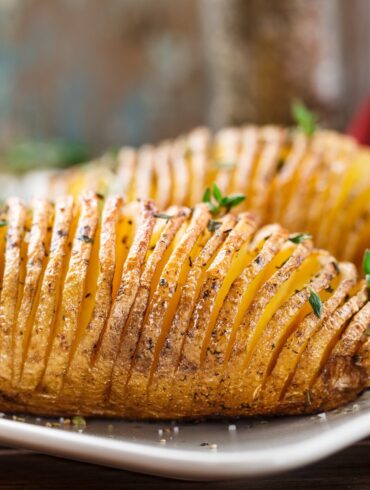 Two Hasselback Potatoes on a white plate