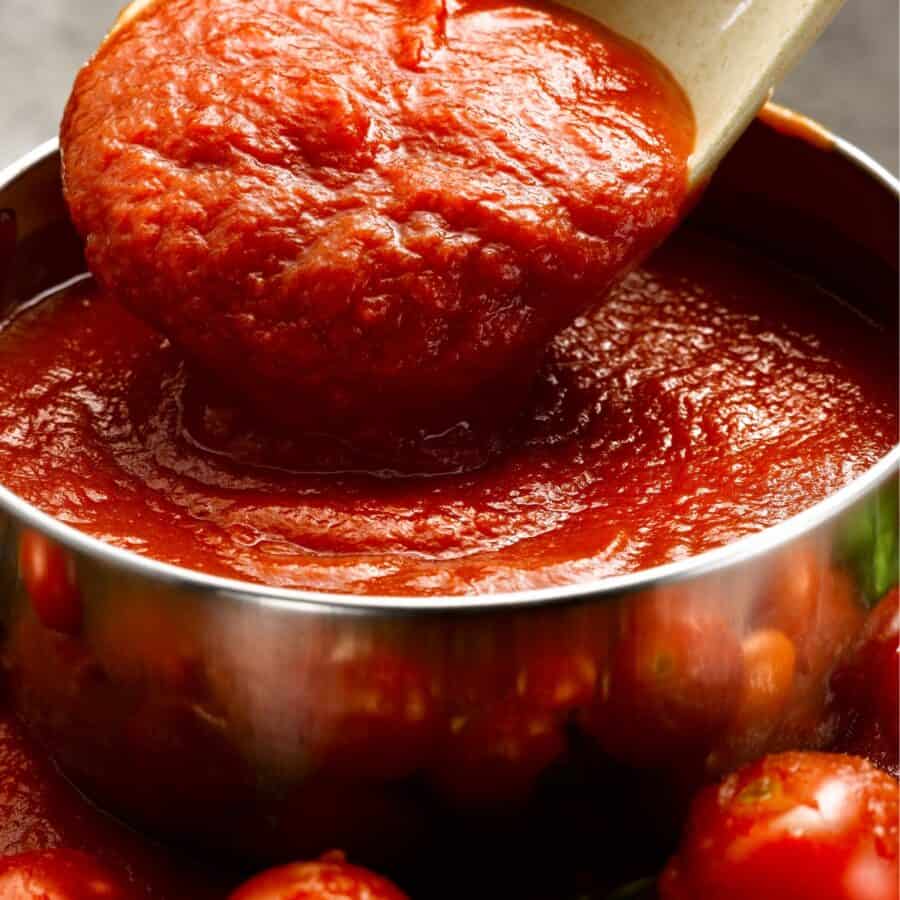 Homemade Pizza Sauce in a bowl being served with a spoon