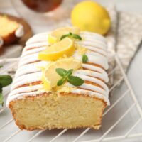 Close up image of lemon yogurt cake on a cooling rack with sliced lemon garnish