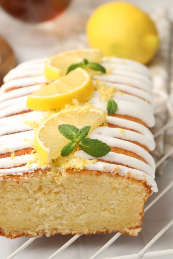 Close up image of lemon yogurt cake on a cooling rack with sliced lemon garnish
