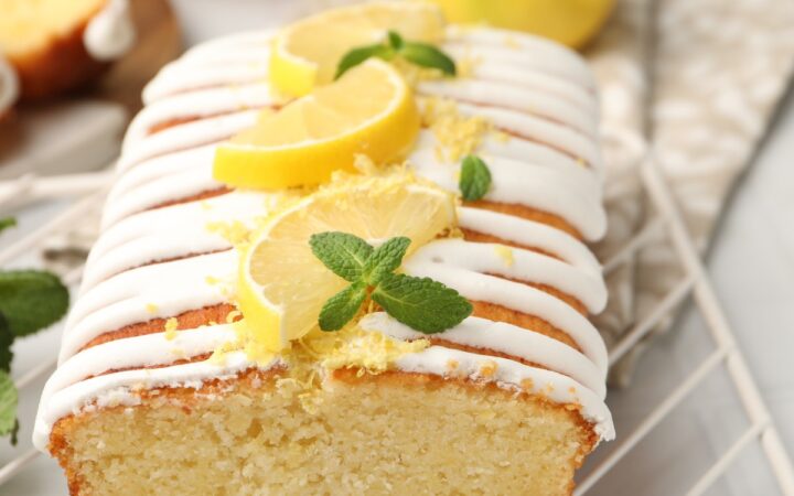 Close up image of lemon yogurt cake on a cooling rack with sliced lemon garnish