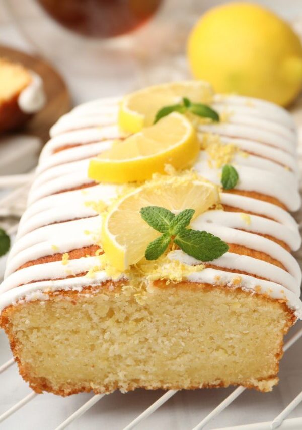 Close up image of lemon yogurt cake on a cooling rack with sliced lemon garnish
