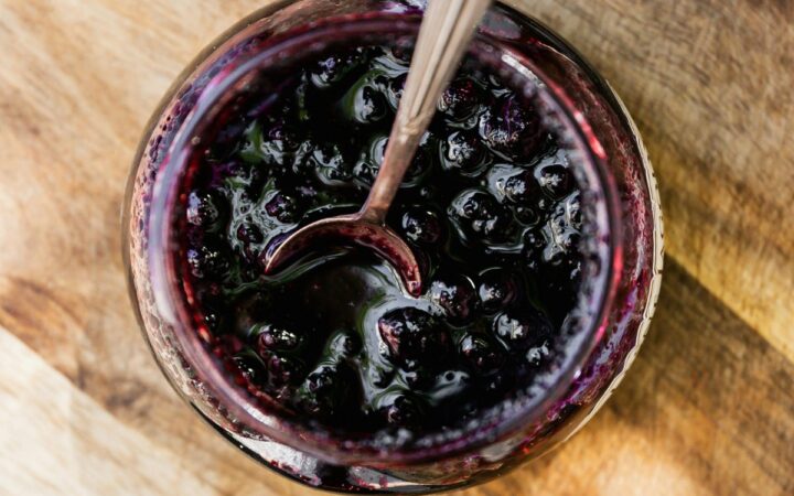 Overhead image of Blueberry Compote in a glass jar with a serving spoon
