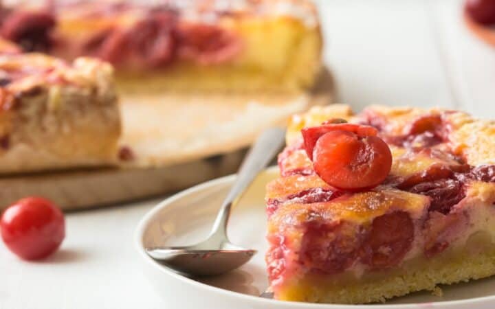 Close up image of a slice of Cherry Clafoutis on a white plate